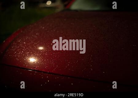 Raindrops on car in dark. Car at night in parking lot. Car in rain. Overnight parking in detail. Stock Photo