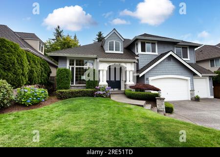 Beautiful home with green grass yard and blooming hydrangea flowers in summer season Stock Photo