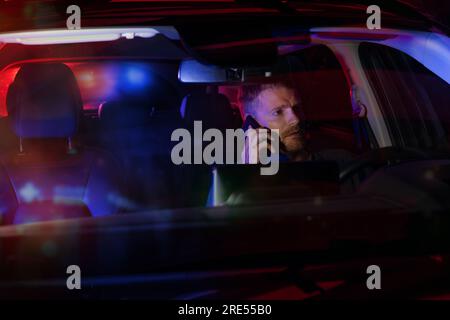 man sitting inside a car and talking on the phone after being stopped by police at night Stock Photo