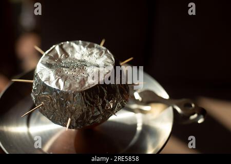 Foil on hookah. Ignition of coals in hookah. Smoking is harmful to health. Ash bowl. Stock Photo