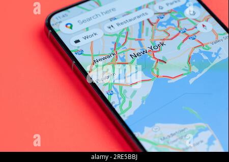 New York, USA - July 21, 2023: Car traffic on New York google maps on smartphone screen close up view with red background Stock Photo