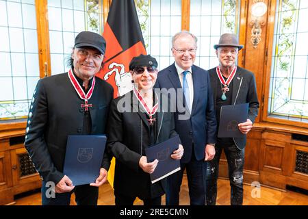 Hanover, Germany. 25th July, 2023. Matthias Jabs (l-r), band member of the 'Scorpions', Klaus Meine, band member of the 'Scorpions', Stephan Weil (SPD), Minister President of Lower Saxony, and Rudolf Schenker, band member of the 'Scorpions', stand in the guest house of the state government after receiving the Grand Cross of Merit of the Order of Merit of Lower Saxony. Three band members of the rock band 'Scorpions' are honored for their music as well as their honorary commitment in Lower Saxony. Credit: Michael Matthey/dpa/Alamy Live News Stock Photo