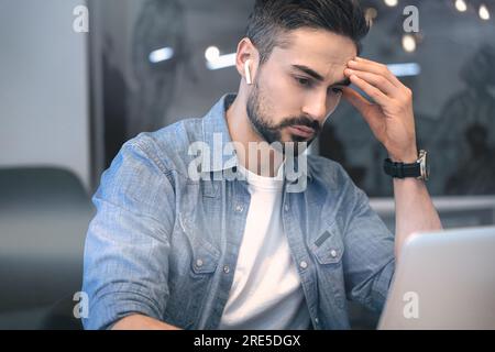 Software designer working on a new project while using a laptop, looking at a screen. Handsome brunette manager in an office. The startup, coworking Stock Photo