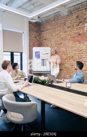 Successful businesswoman making a team presentation in a meeting room in a creative office. The startup, coworking, and management concept Stock Photo