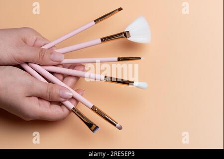 Make up artist theme. Different size brushes in woman hand on beigr color background Stock Photo
