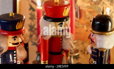 Three traditional nutcrackers with red candles in the background. Christmas mood. Festive. Stock Photo