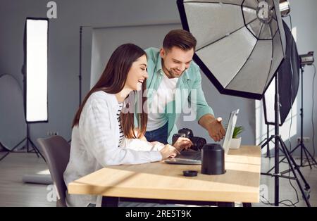 Photographers looking at photographs on laptop in professional studio Stock Photo