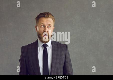 Crazy amazed adult caucasian businessman with opened mouth looking aside Stock Photo