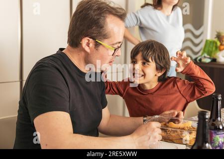 boy playing scare his family in the kitchen Stock Photo