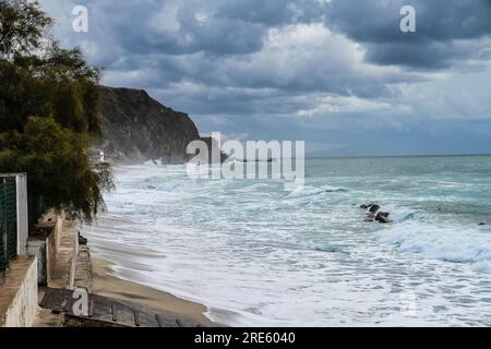 Turquoise gulf bay of Cape Capo Vaticano, Calabria, Southern Italy. Sandy beach, green mountains and plants, blue sky, white clouds, cliffs platform Stock Photo