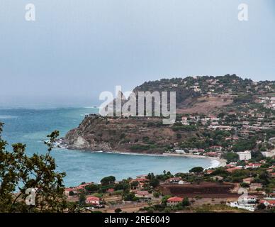 Turquoise gulf bay of Cape Capo Vaticano, Calabria, Southern Italy. Sandy beach, green mountains and plants, blue sky, white clouds, cliffs platform Stock Photo