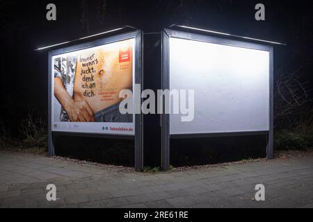 Two billboards illuminated at night . One warns of venereal diseases, the other is empty. Stock Photo