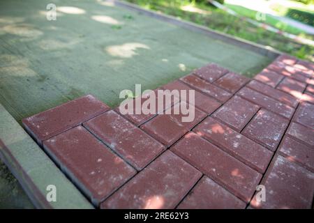 Unfinished pedestrian walkway made of rectangular red paving stones. Stock Photo
