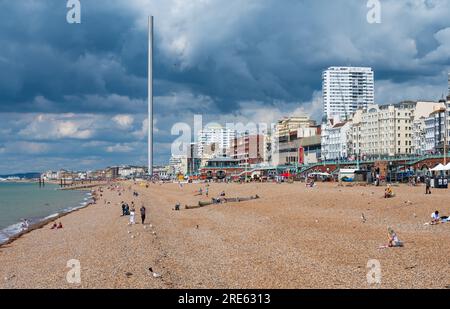 People on the beach looking West along the coastline, on an overcast cloudy dull Summer day at the British seaside resort of Brighton & Hove, UK. Stock Photo