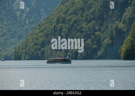 A tranquil scene of a ferry making its journey across the serene waters of Königssee lake, against the beautiful backdrop of Bavaria, Germany. Stock Photo