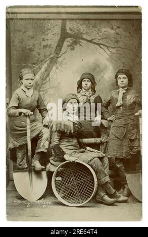 Original Victorian studio portrait printed as a souvenir postcard of Pit Brow girls and Screen Lasses with tools of trade, posted June 9th 1908 but photographed in 1887 by Herbert Wragg at an unknown coalfield in Wigan, Lancashire, England, U.K. Stock Photo
