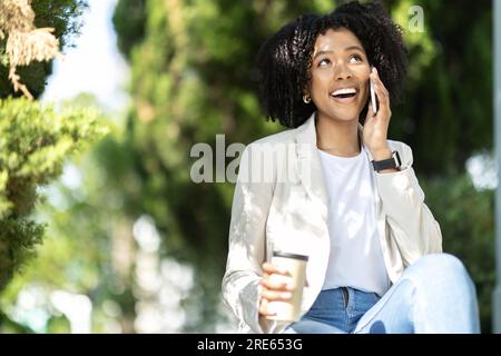 Pretty young black woman have phone call, drinkng coffee Stock Photo