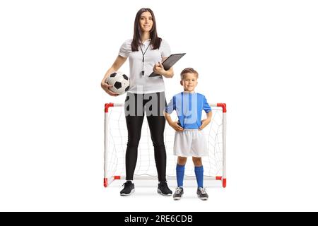 Female football coach with a whistle holding a clipboard and standing with a boy in front of mini goals isolated on white background Stock Photo