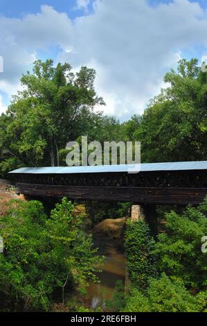 Clarkson Covered Bridge in Cullman, Alabama is a long, weathered, wooden bridge that spans Crooked Creek. Stock Photo