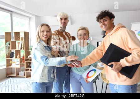 Team of graphic designers putting hands together in office Stock Photo