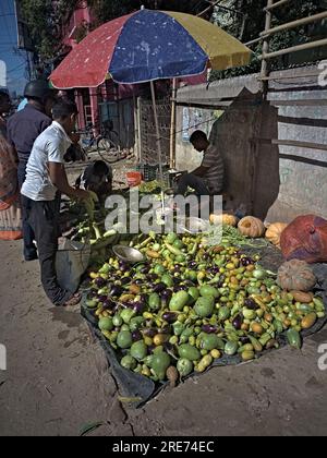 23.07.2023. Raiganj, India. An Indian vegetable seller sitting under the umbrella in a market. Stock Photo
