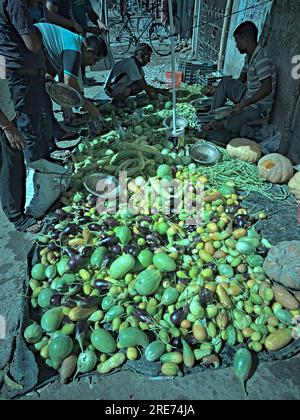 23.07.2023. Raiganj, India. An Indian vegetable seller sitting under the umbrella in a market. Stock Photo