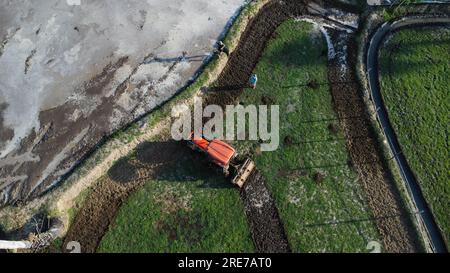 Aerial view of a tractor in a field plowing the land in preparation for sowing. Farmer in tractor preparing land with seedbed cultivator. Stock Photo