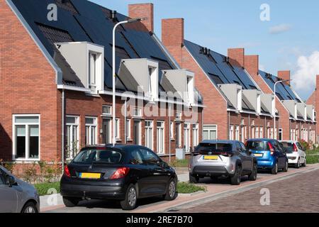 Street with modern social single-family new-build homes with solar panels on roof in the Netherlands. Sustainable energy. Electric power generation Stock Photo