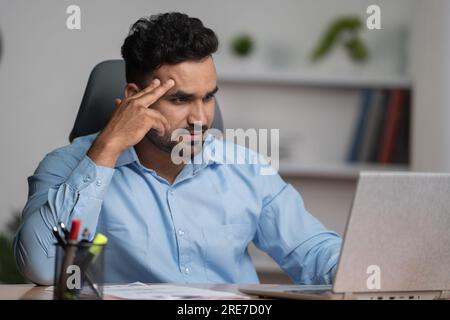 Worried indian Businessman or entrepreneur after seeing mail on laptop at office - concept of work pressure, Business challenges and Uncertain future. Stock Photo