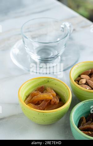 Dried fruits in a small round glass bowl next to a glass on a ceramic table. Delicious and healthy drink. Selective focus. Stock Photo