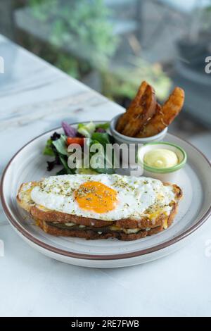 Classic French toast with cheese and ham, fried eggs, vegetables, and honey-balsam dressing. Stock Photo