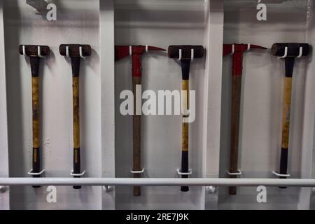 Set of sledge hammers and fireman's axes secured on the wall. Stock Photo