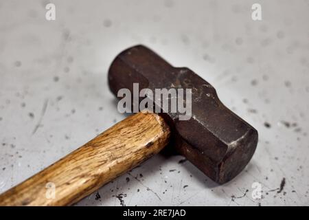 Dirty Metal hammer with wooden handle lying on the working table. Stock Photo