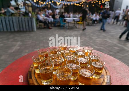 Small glasses filled with brandy on a wooden tray. Alcoholic buffet in street cafe. Shots with alcoholic beverage for taste. Stock Photo