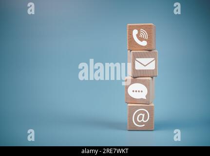 Stacked wooden blocks and communication icons. Website page, contact us or email marketing concept, customer support hotline, contact us, email, phone Stock Photo