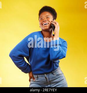 Happy, phone call and black woman in studio laugh, silly or share joke on yellow background. Funny, talking and African lady with goofy, gossip or Stock Photo