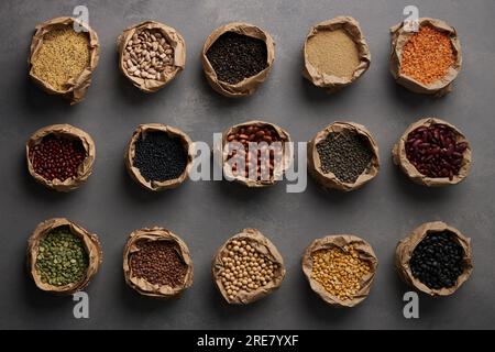 Various pulses, lentils, legumes and beans in brown paper bags on grey background Stock Photo