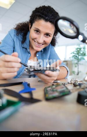 female engineer looking at circuit through magnifying glass Stock Photo