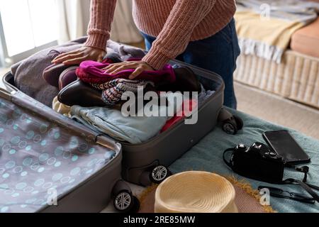 Hands of biracial woman packing suitcase in bedroom Stock Photo