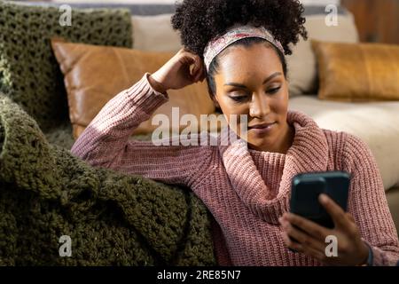 Happy biracial woman using smartphone at home Stock Photo