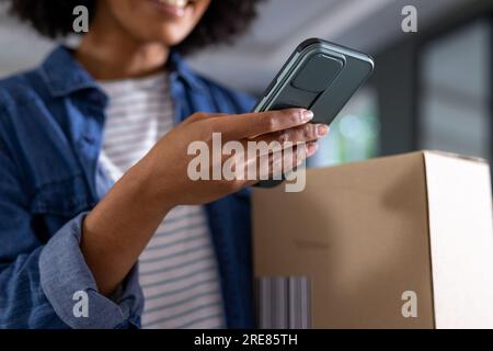 Happy biracial woman using smartphone at home Stock Photo