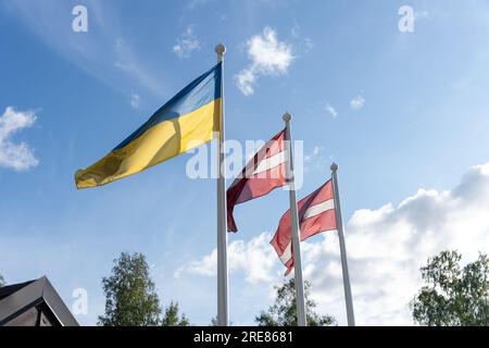 Ukrainian and Latvian flags together on flag poles waving in wind Stock ...
