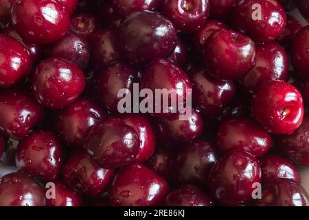 An extreme close-up of a bunch of fresh washed cherries in an overhead view, showing their details and textures. The cherries are bright red and gloss Stock Photo