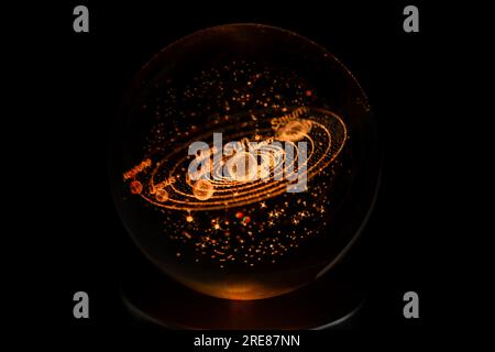 Laser engraved model of the Solar System, including Earth, inside a glass ball. Solar System in Milky Way Galaxy on black background. Space, galaxies... Stock Photo