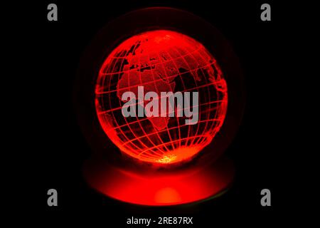 World map model engraved with a laser inside a glass globe. World map with neon red backlight on isolated black background. Earth and crisis concept. Stock Photo
