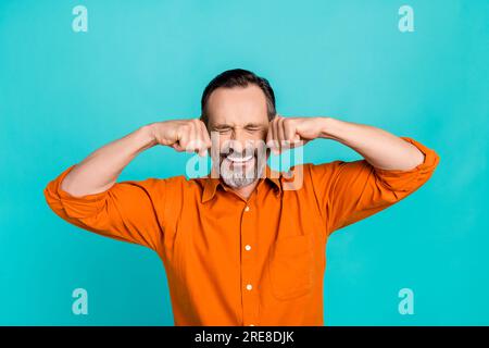 Photo of funny old businessman crying tears wear orange shirt fists ears bankruptcy problems isolated on aquamarine color background Stock Photo