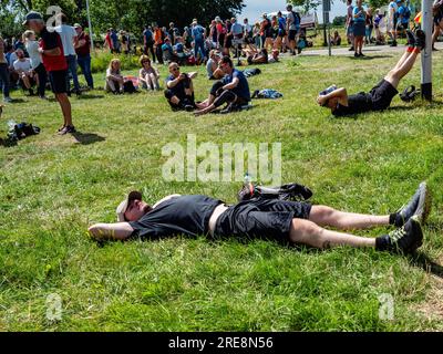 July 18, 2023, Close to Bemmel, Netherlands: Participants are seen lying on the grass. Since it is the world's biggest multi-day walking event, The International Four Days Marches (in Dutch 'De Vierdaagse') is seen as the prime example of sportsmanship and international bonding between military servicemen, women and civilians from many different countries. This year, it was the 105 edition and the official amount of walkers registered was 43,363 from 77 countries. Participants can choose to walk 30km, 40km, or 50km per day. On the last day, 39,019 walkers crossed the finish line. After a fes Stock Photo