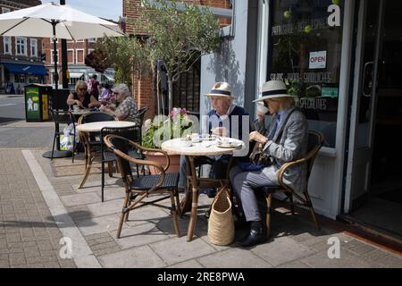 Retired couple wearing Panama Straw hats enjoy lunch in a café along Wimbledon Village High Street, London SW19, England, UK Stock Photo