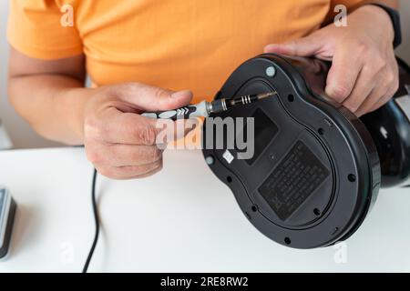 A man sits at a table and does repairs, repairs a small coffee maker with a screwdriver. Close-up Stock Photo