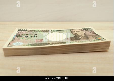 Ten thousand yen (10,000 yen) banknotes stacked. Japanese money. Paper money. isolated on wooden table. Side view. Stock Photo